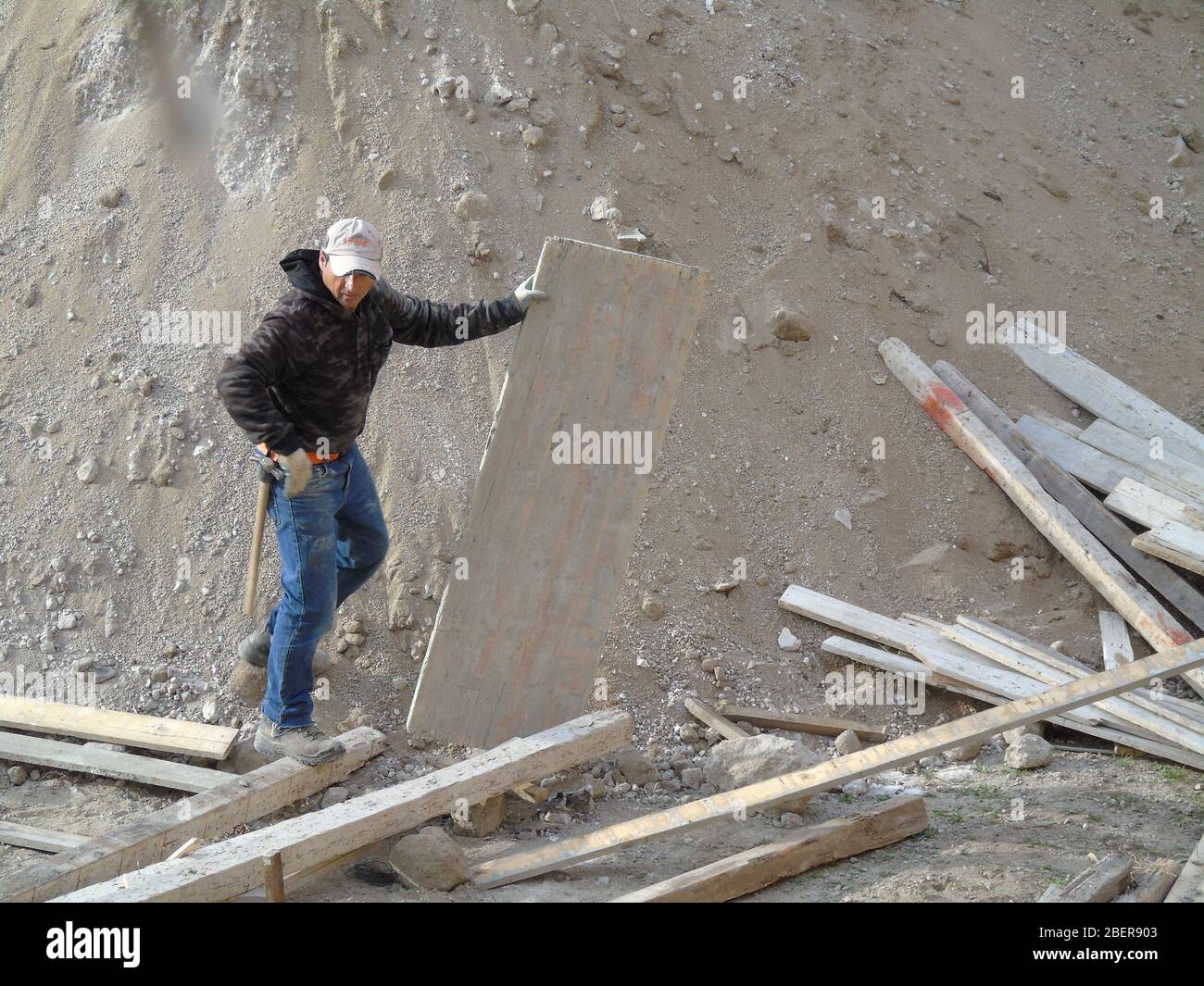 Worker handling wooden axis in a construction site Stock Photo - Alamy