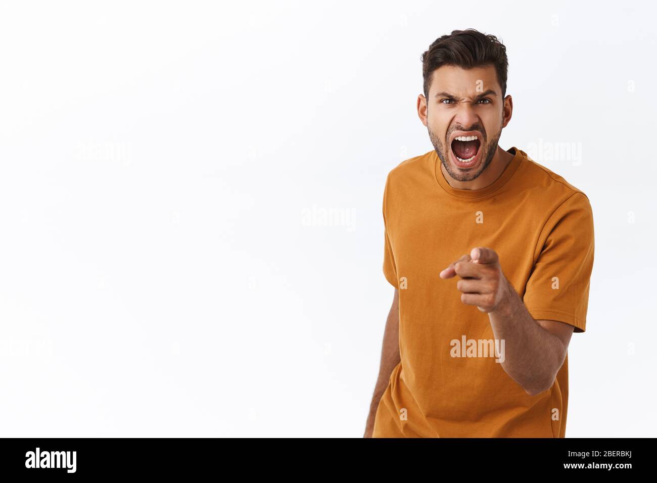 Angry, distressed outraged young man with beard, losing temper and accusing someone, swearing, say rude words during argument, pointing camera as Stock Photo