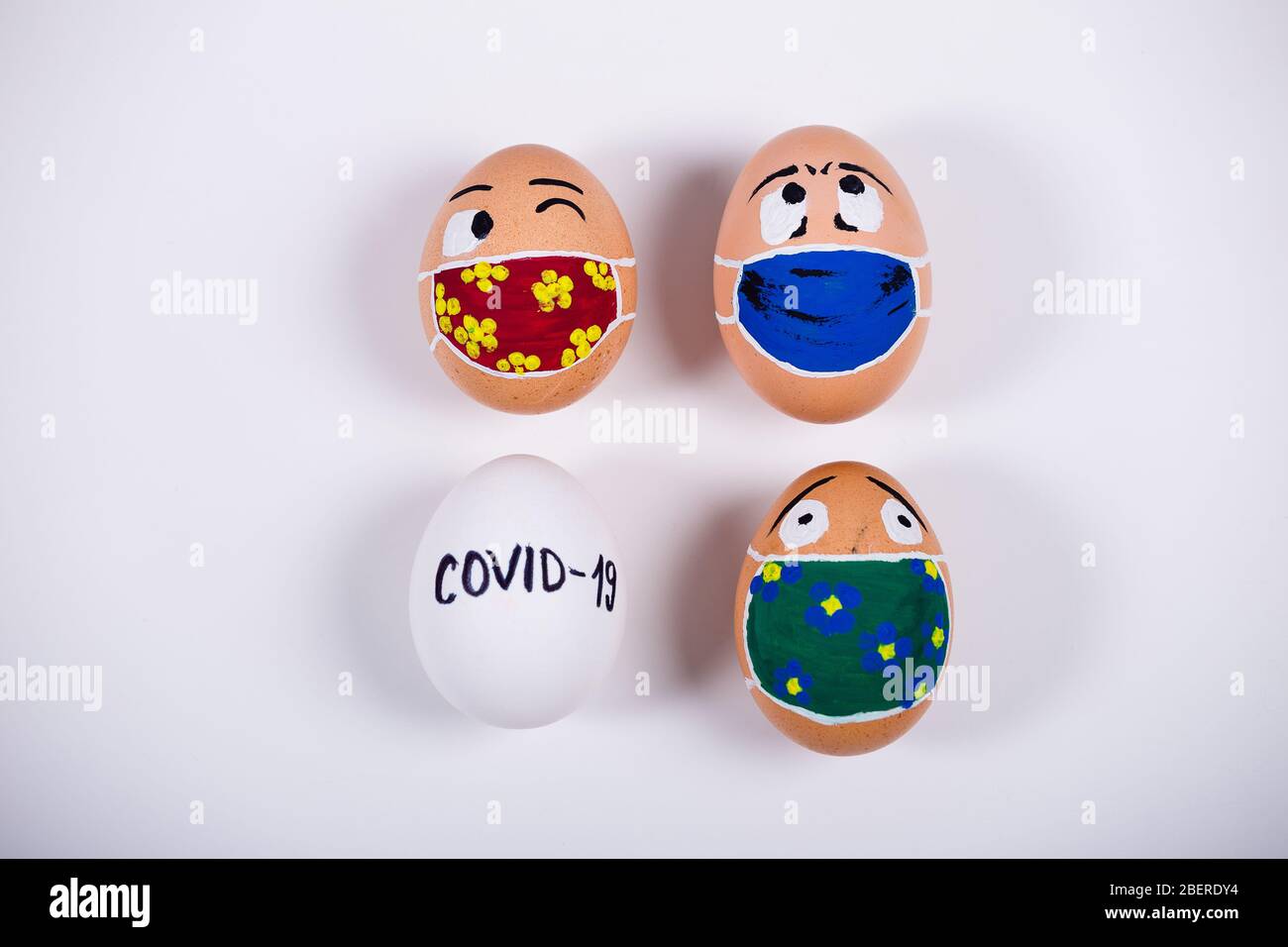 Diverse chicken eggs with doodle faces wearing medical masks. Conceptual image of Easter during Corona virus epidemic lockdown. Quarantine at home. Stock Photo