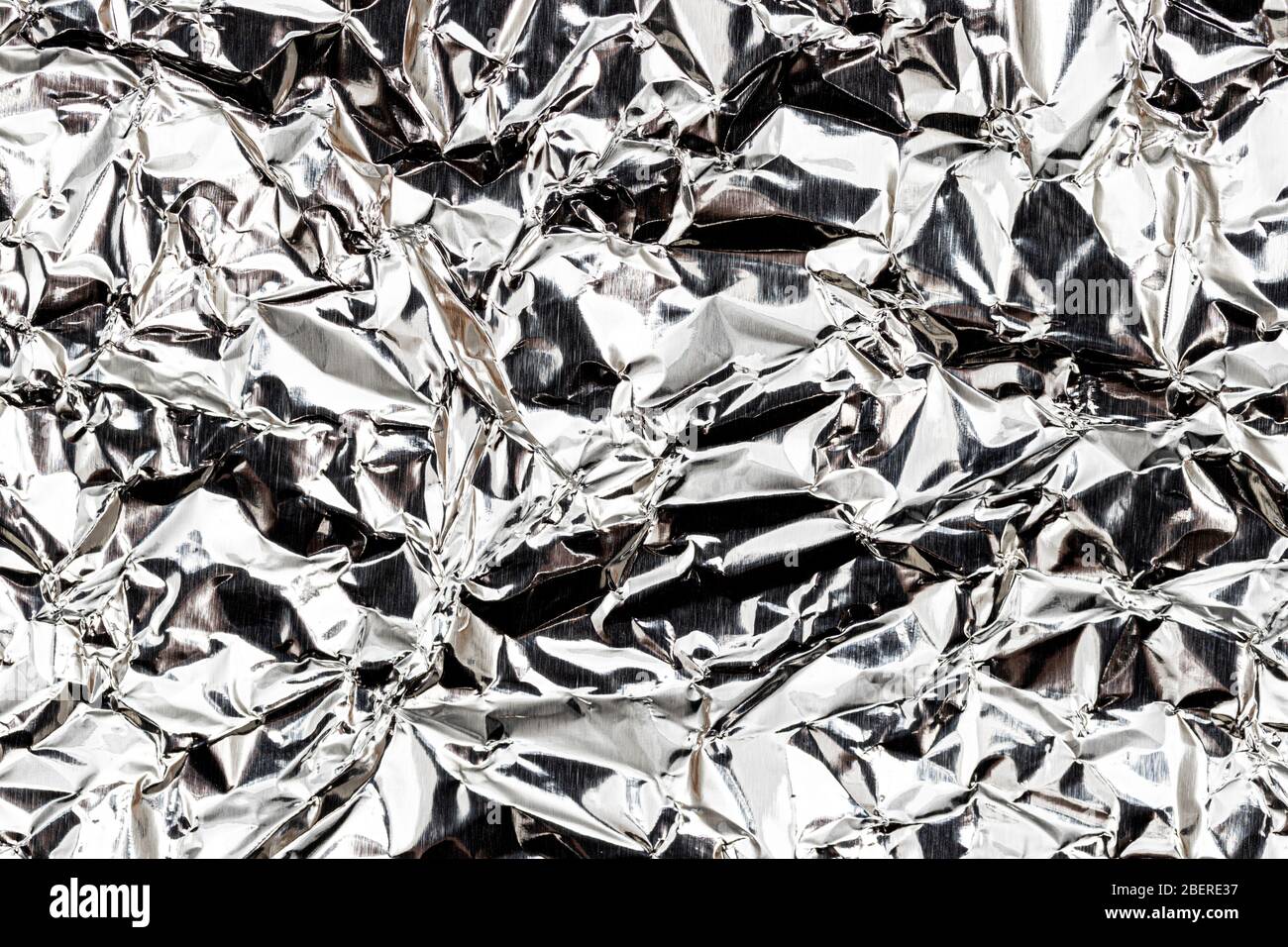 Texture of crumpled aluminum kitchen foil. Silver abstract backdrop for