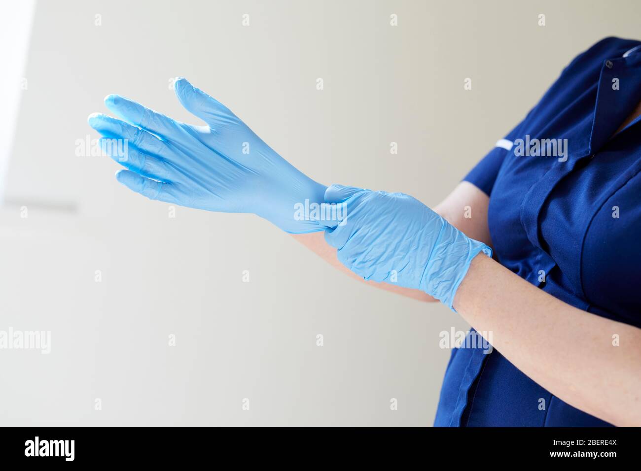 Nurse putting on vinyl gloves Stock Photo