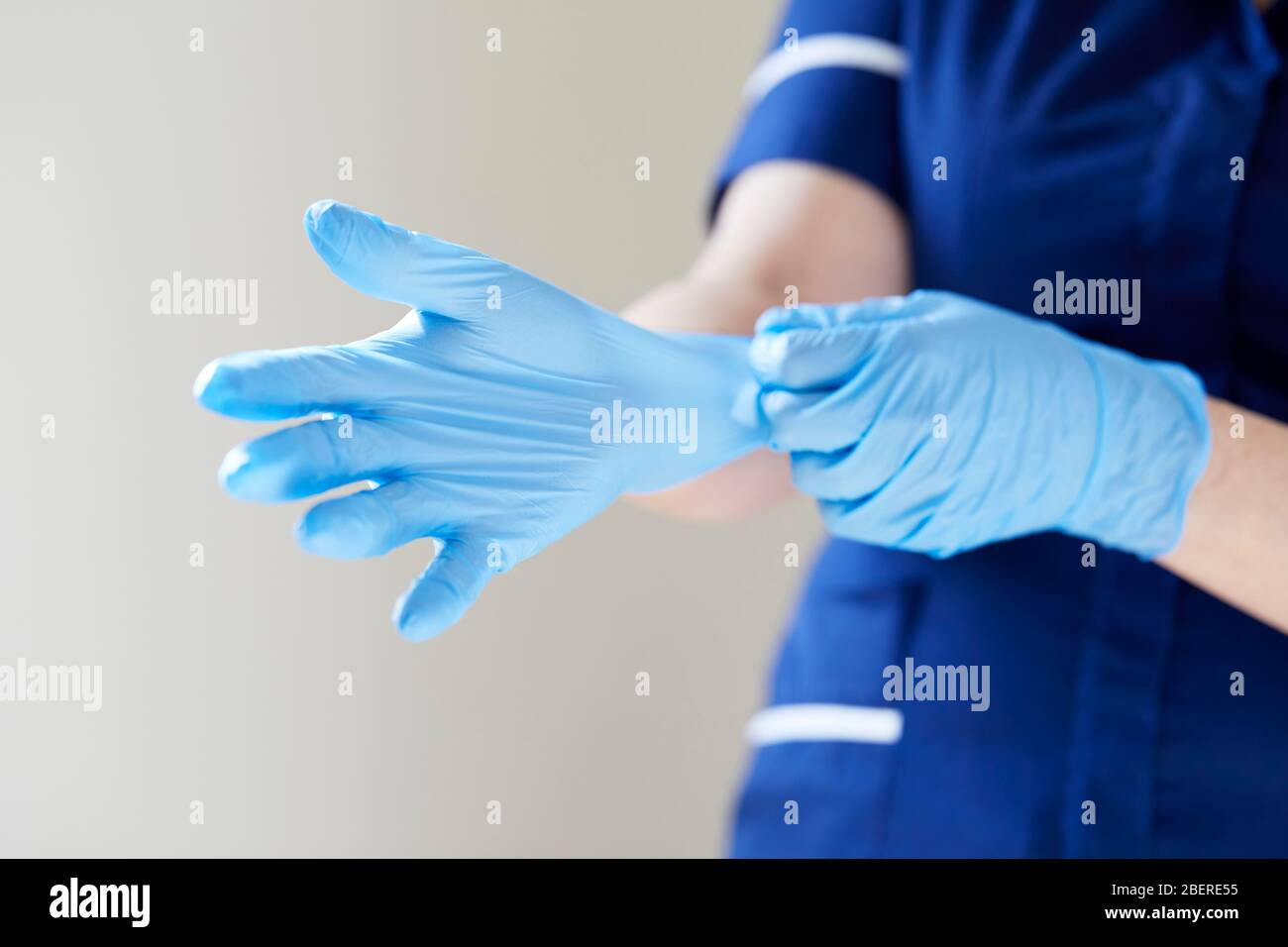Nurse putting on vinyl gloves Stock Photo