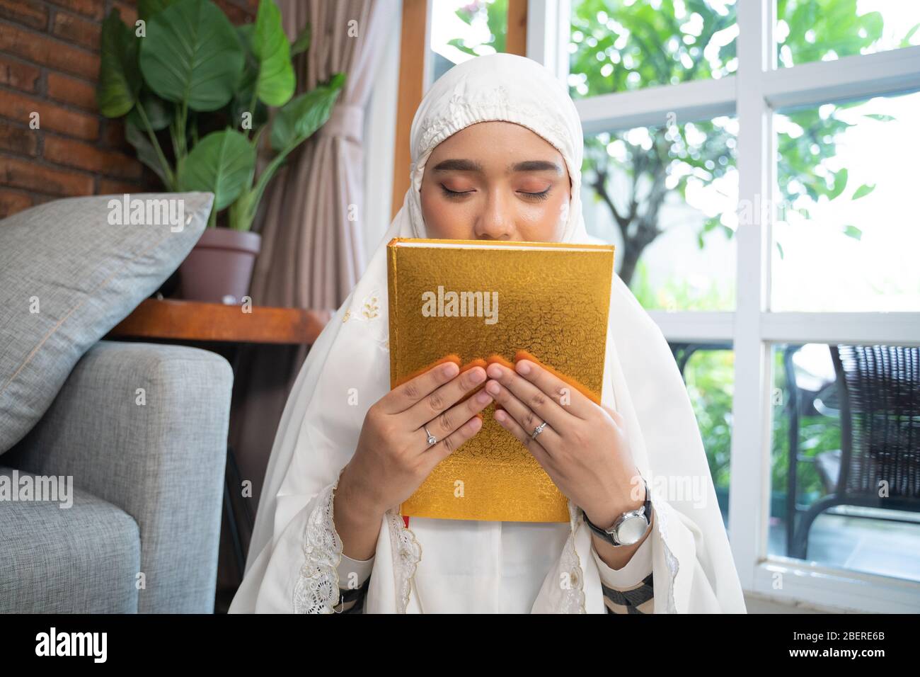 beautiful muslim woman kissing quran at home Stock Photo Alamy