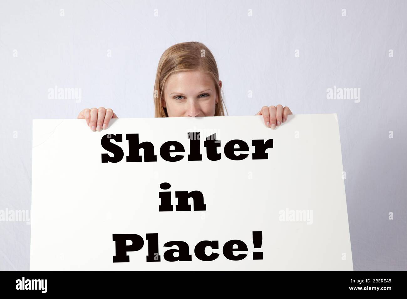 Woman holding a sign that says 'Shelter in Place!' Stock Photo