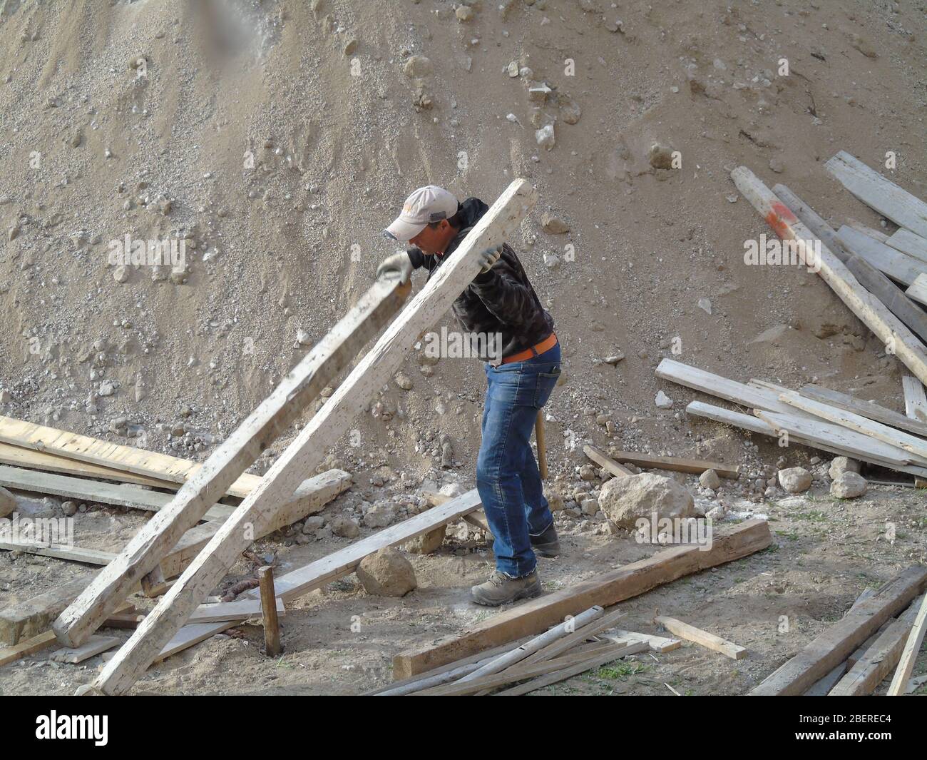 Worker handling wooden axis in a construction site Stock Photo - Alamy