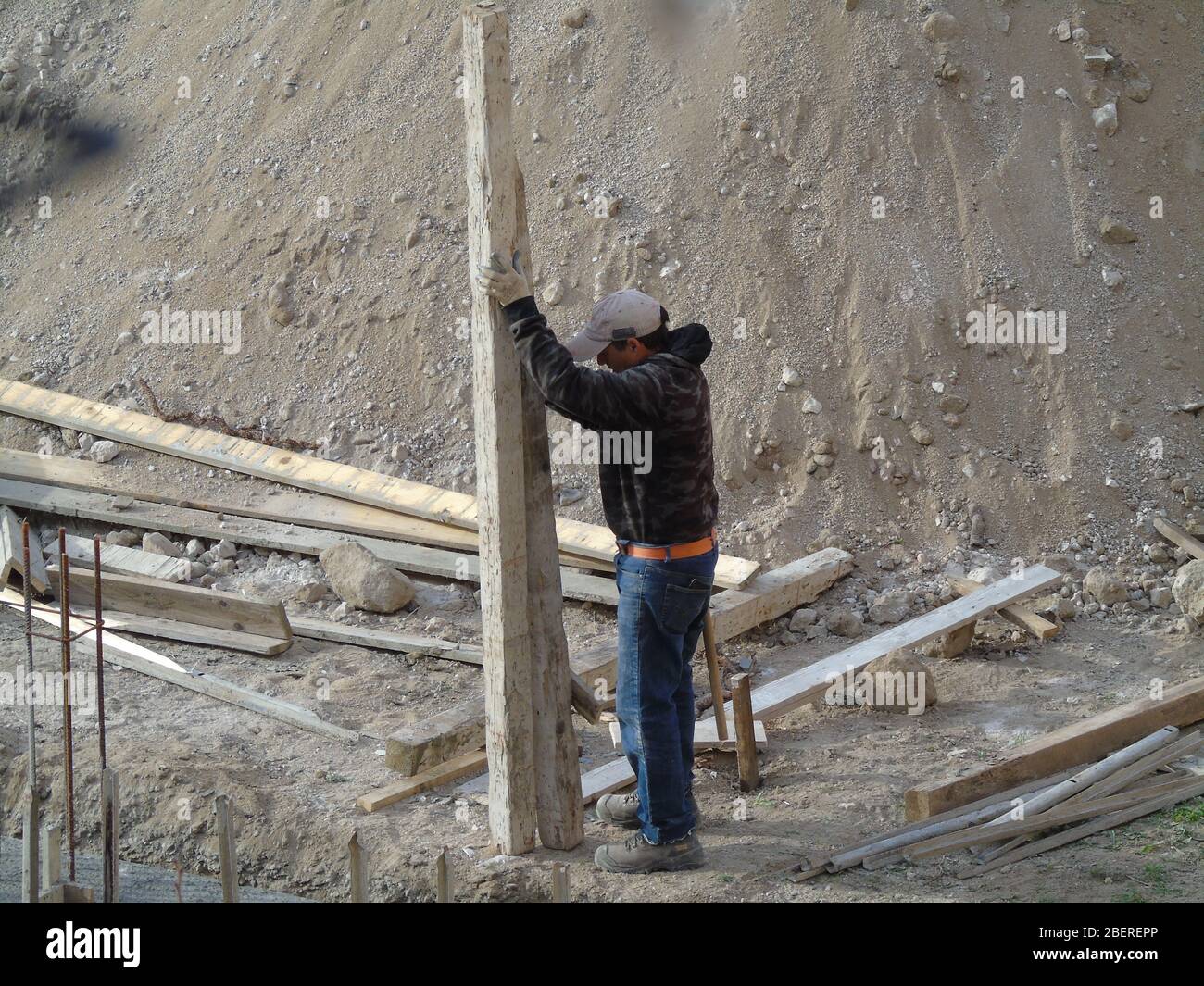 Worker handling wooden axis in a construction site Stock Photo - Alamy