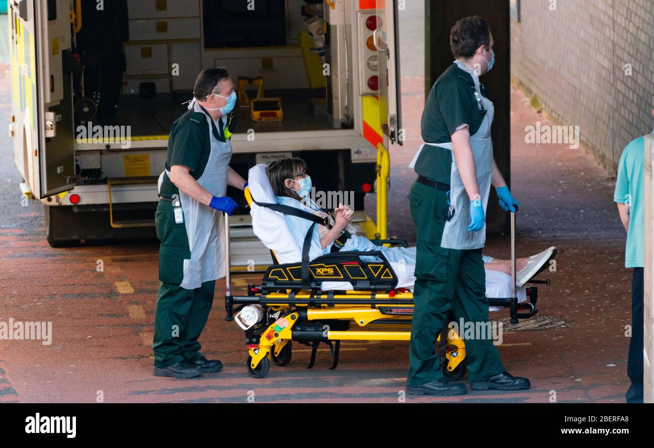 Glasgow, Scotland, UK. 15 April 2020. Patient is unloaded from ambulance by staff wearing PPE at A&E department at Glasgow Royal Infirmary. Iain Masterton/Alamy Live News Stock Photo