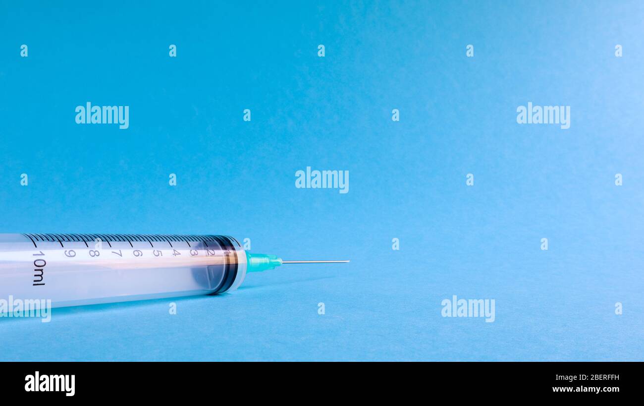 On a blue background lies a medical syringe with a needle. epidemic ...