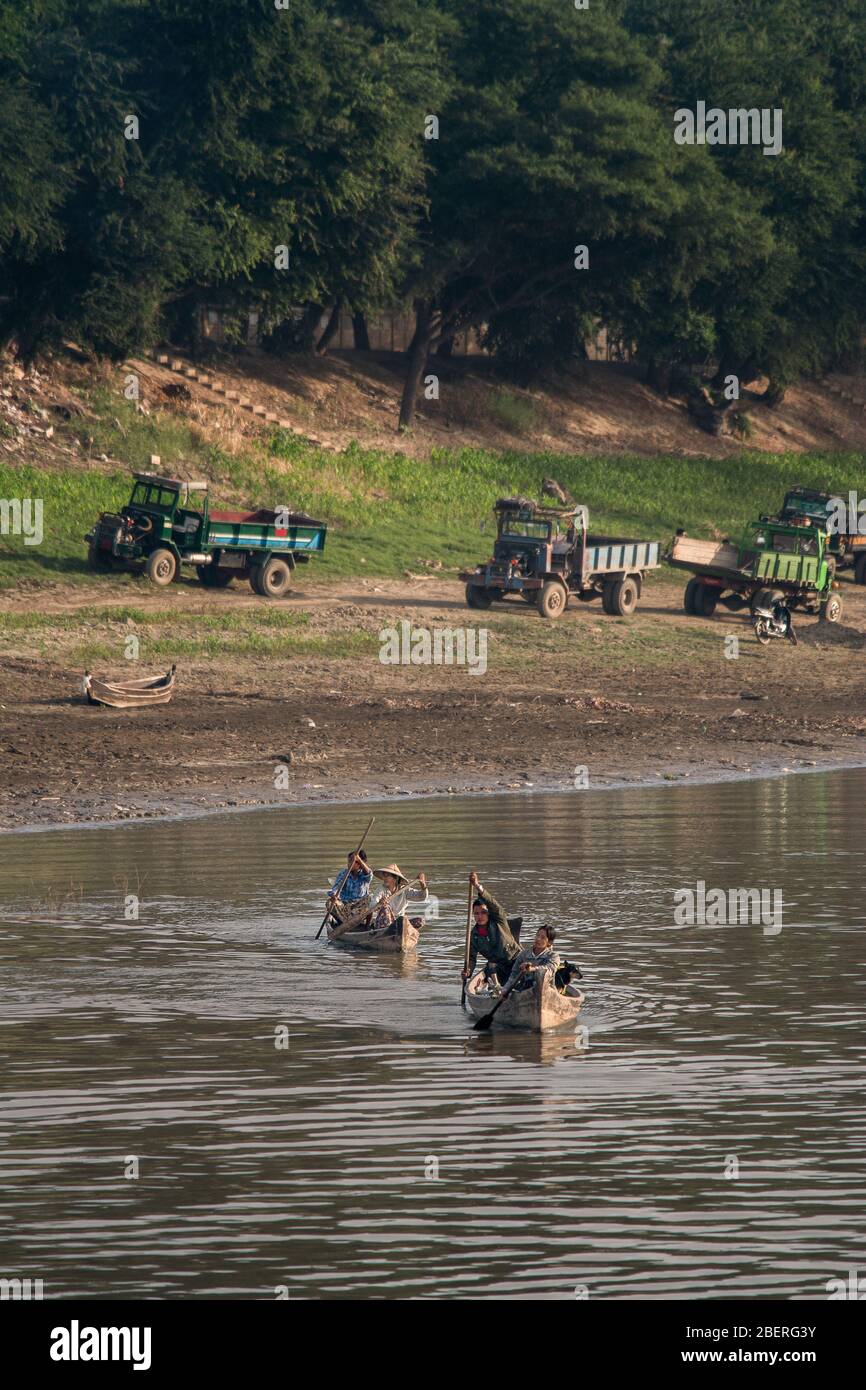 Locals of Bagan Myanmar row their wooden canoes along the Irrawaddy River. Stock Photo