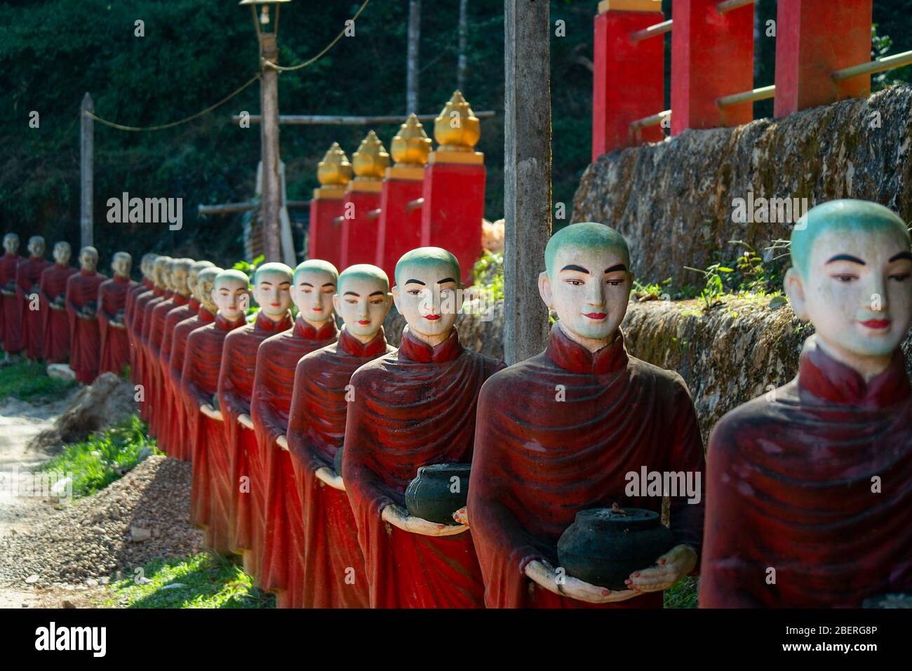 A long row of colourful buddhist monk statues at the entrance of the Kaw Ka Thaung cave temple. Stock Photo