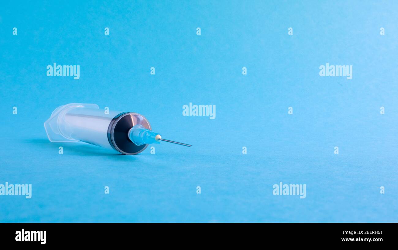 On a blue background lies a medical syringe with a needle. epidemic ...