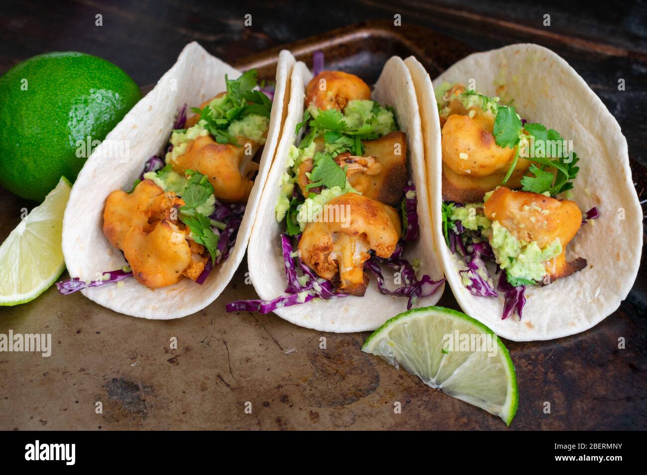 Buffalo Cauliflower Tacos with Avocado Crema: Vegetarian tacos made with spicy cauliflower, avocado crema, and shredded cabbage Stock Photo