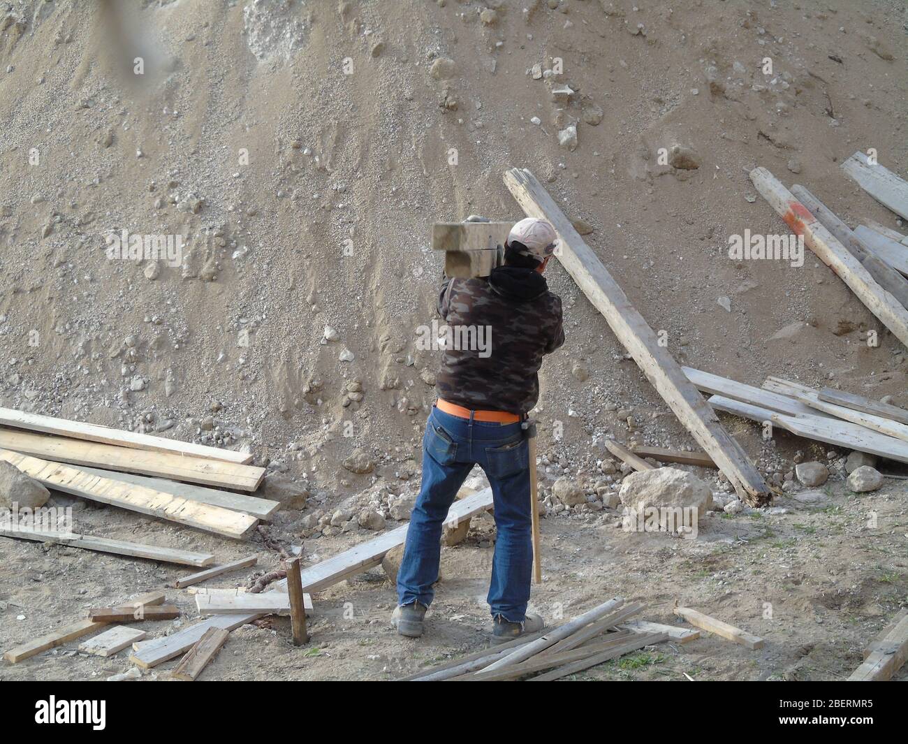 Worker handling wooden axis in a construction site Stock Photo - Alamy