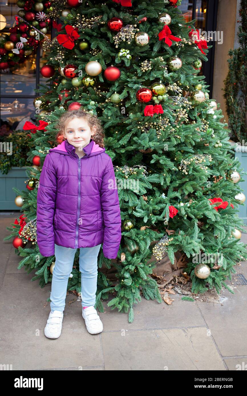 Girl posing by a shopfront Christmas Tree Stock Photo