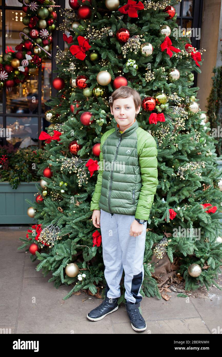 Boy posing by a shopfront Christmas Tree. Stock Photo
