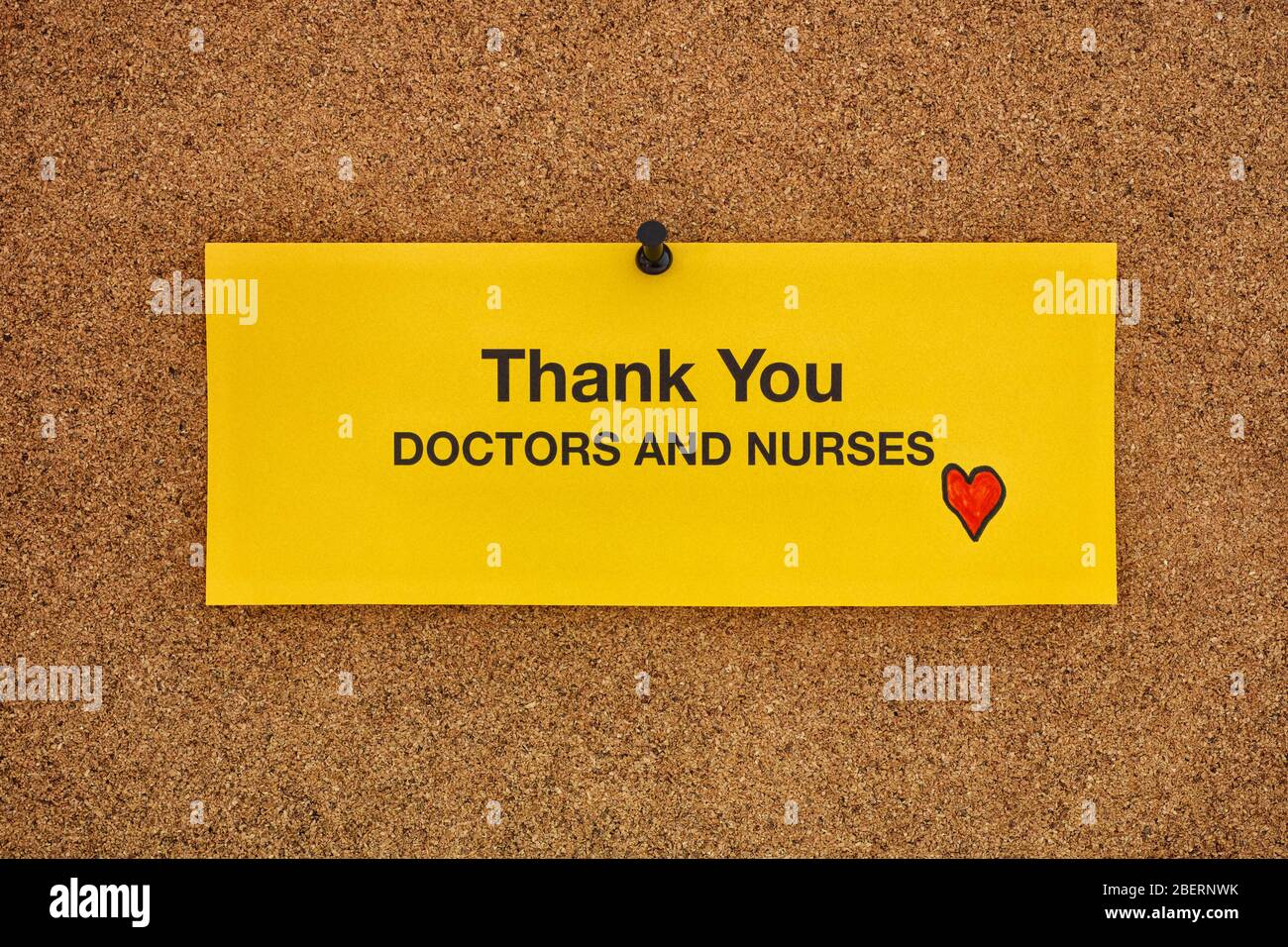 Thank you doctors and nurses written on a yellow piece of paper that is on a bulletin board. Coronavirus concept. Close up. Stock Photo