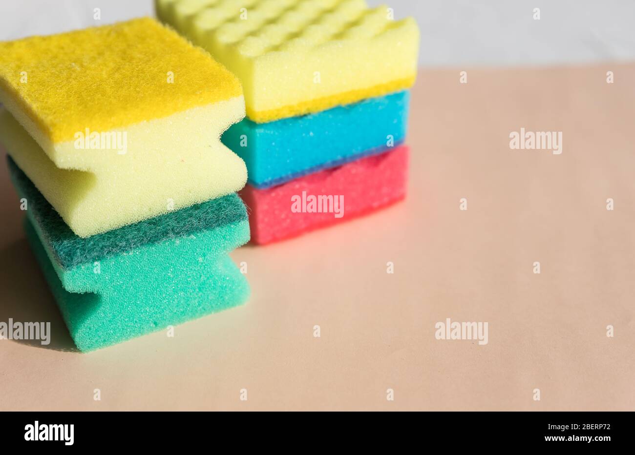 Brightly colored sponges on beige background with copy space.Bright