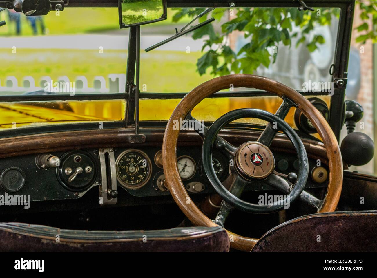 View from the back seat of a Vintage car. Wooden steering wheel, dash board and instruments. Stock Photo