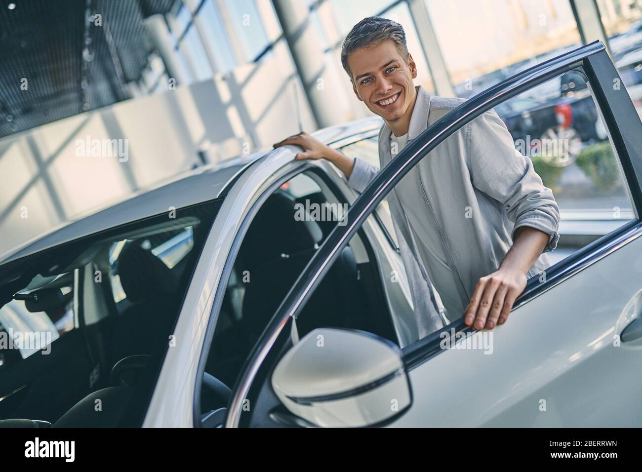 Happy man standing next to car door in showroom Stock Photo Alamy