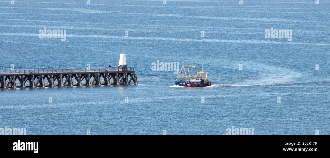 A fishing boat returning to Maryport Harbour in Cumbria Stock Photo