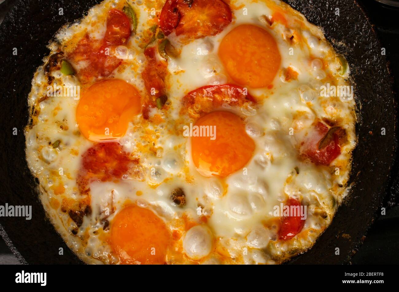 Fried eggs with tomatoes in a pan close-up Stock Photo
