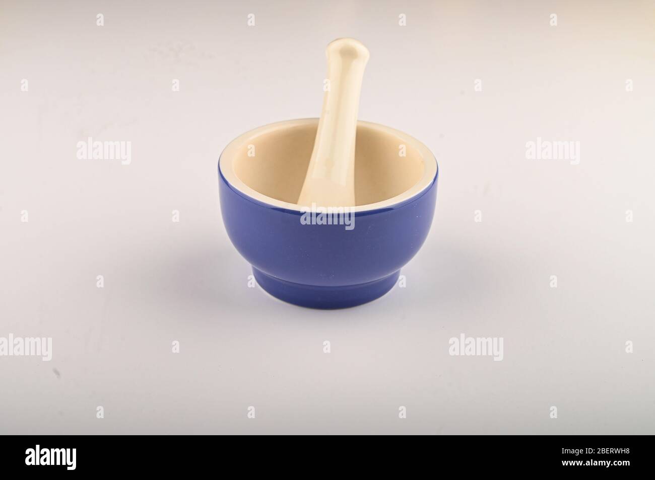Blue ceramic spice mortar with pestle on white background. Close up Stock Photo