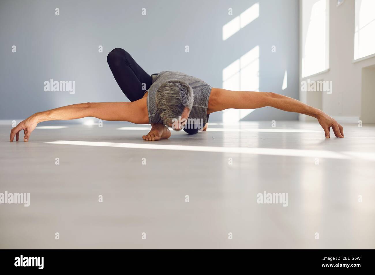 Flexible man practicing yoga in studio Stock Photo
