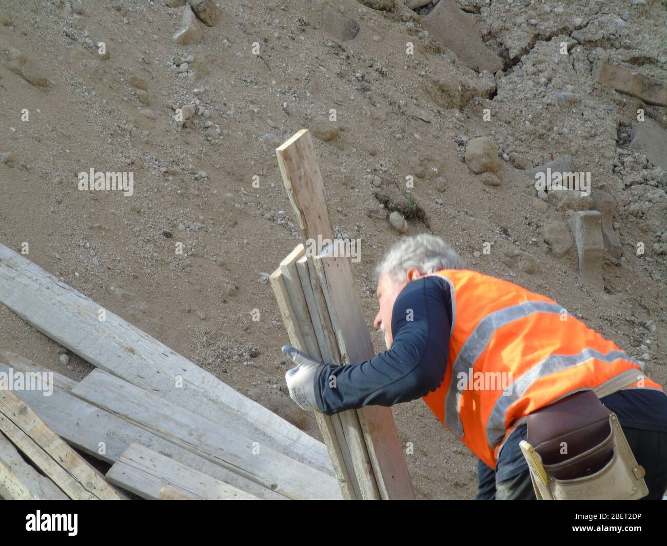Worker on a construction site handling wooden axis Stock Photo - Alamy