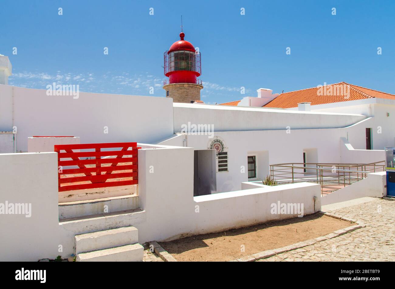 Portugal, Algarve, Cape of St. Vincent in summer, white red lighthouse, red wooden gate on a white building, clear blue sky over lighthouse, lighthous Stock Photo
