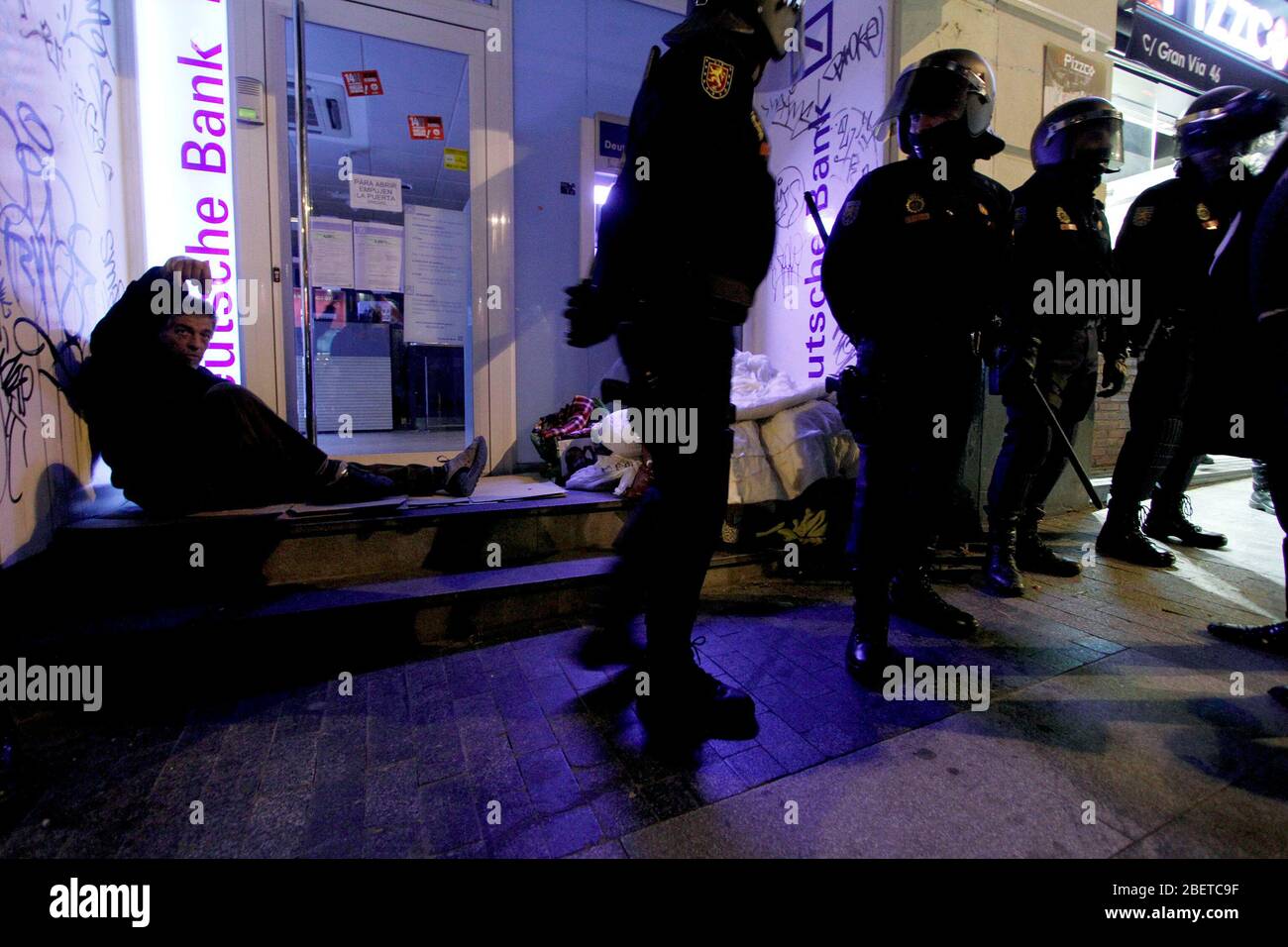 European General Strike.A homeless man sleeps on the door of a bank office surrounded by many members of the National Police.November 14,2012. (ALTERP Stock Photo