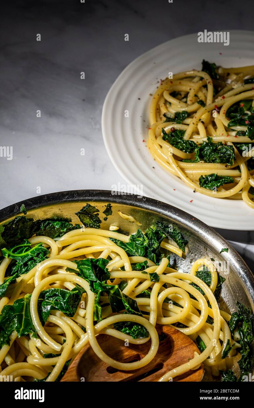 Vegan pasta dish. Bucatini sauteed kale and garlic with nutritional yeast. Stock Photo