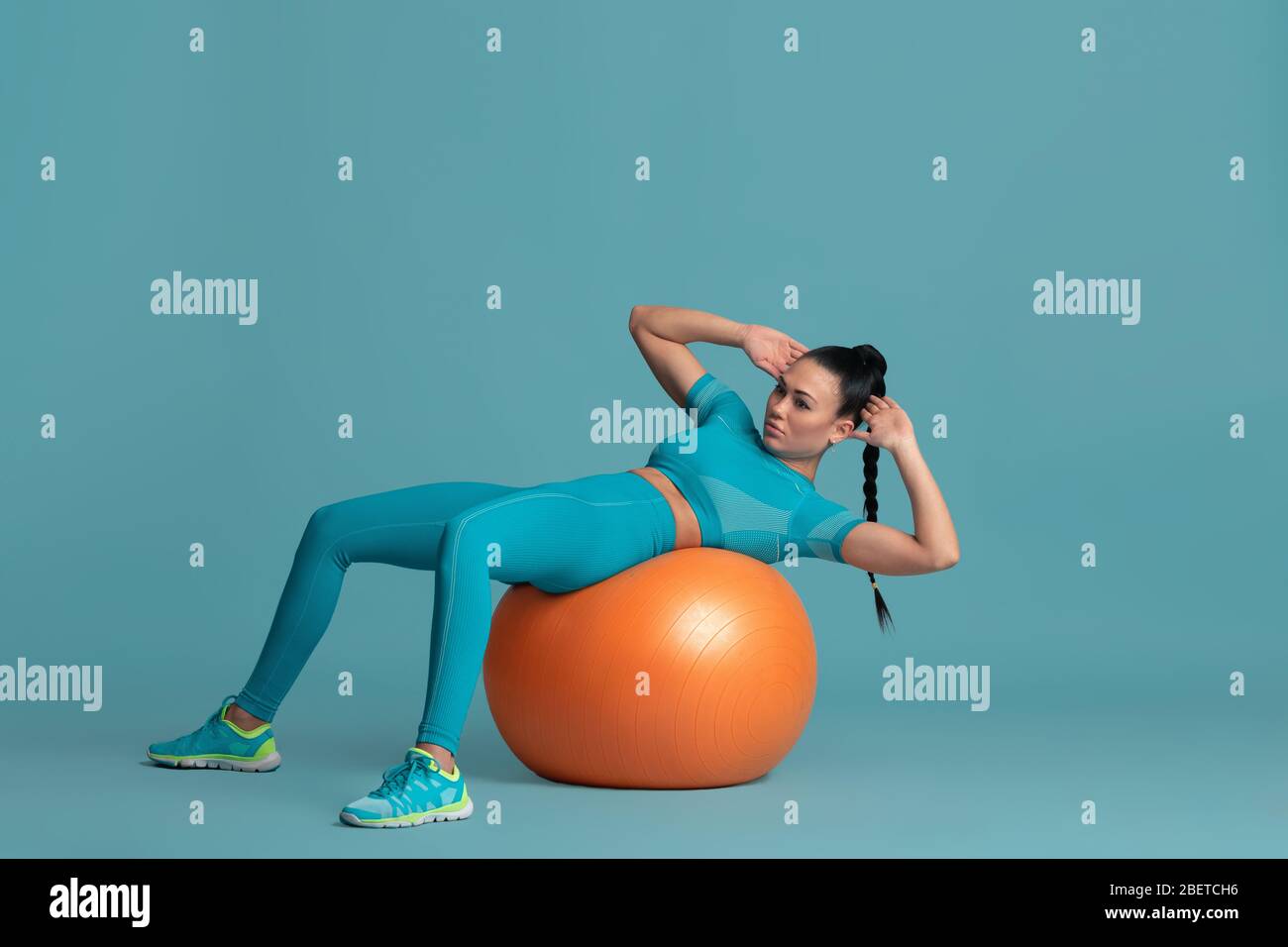 ABS training. Beautiful young female athlete practicing in studio ...