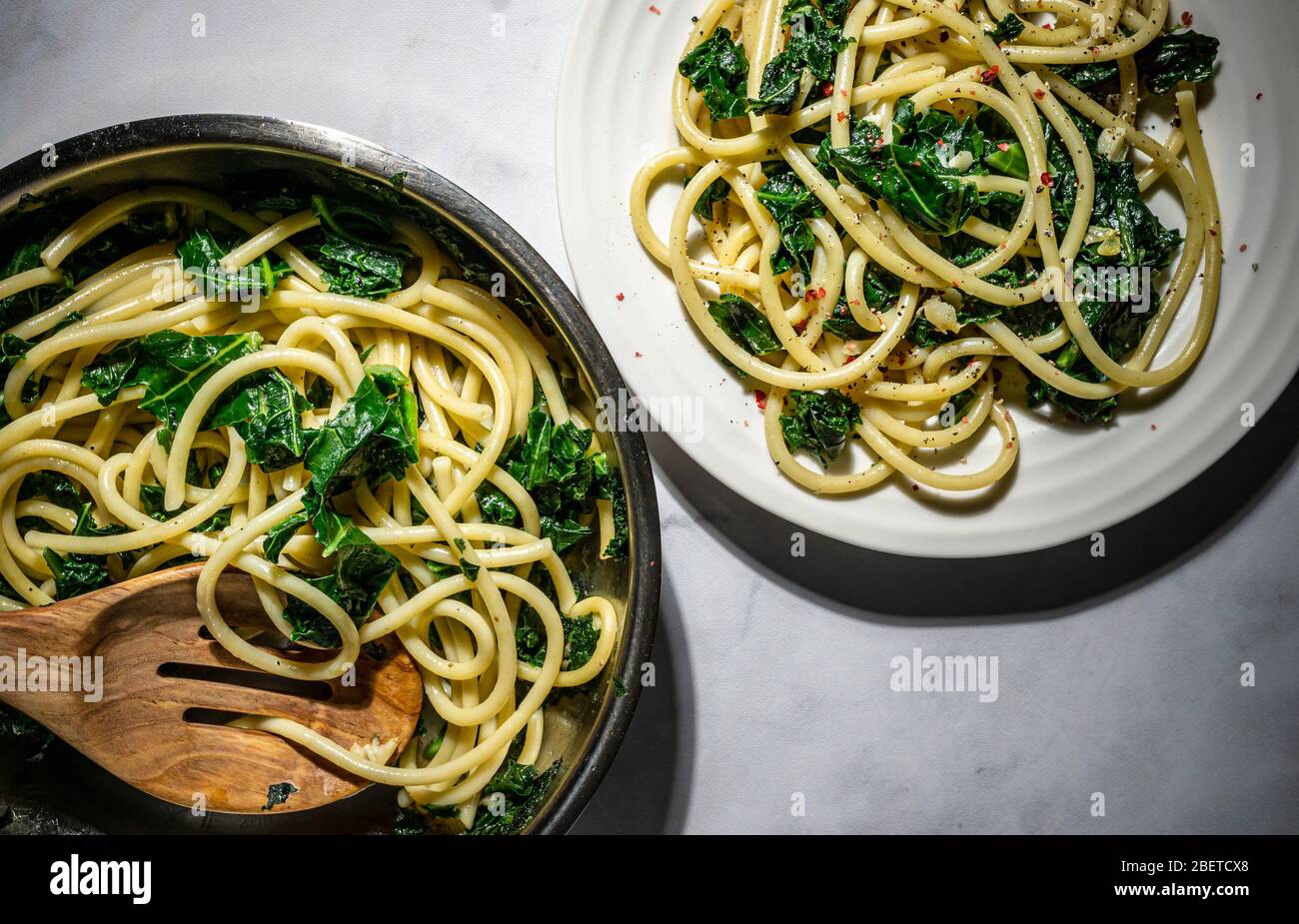 Vegan pasta dish. Bucatini sauteed kale and garlic with nutritional yeast. Stock Photo