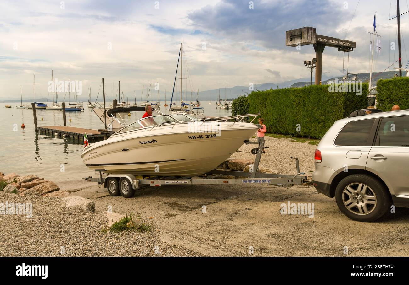 BARDOLINO, LAKE GARDA, ITALY - SEPTEMBER 2018: Car reversing a motor boat on a trailer down the slipway into Lake Garda. Stock Photo