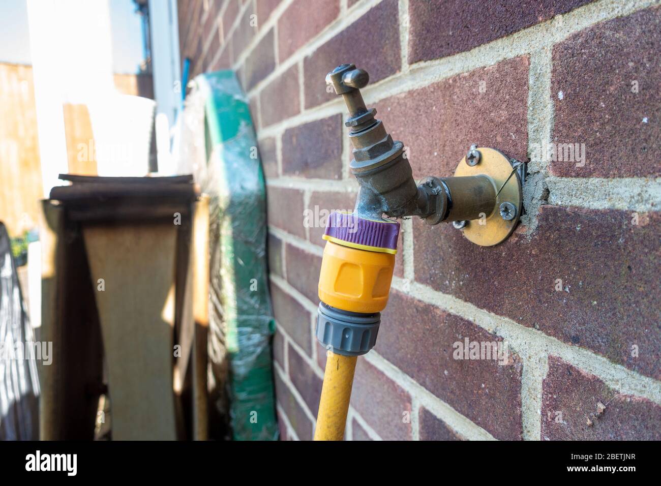 An outdoor garden tap with a hosepipe attached. Stock Photo