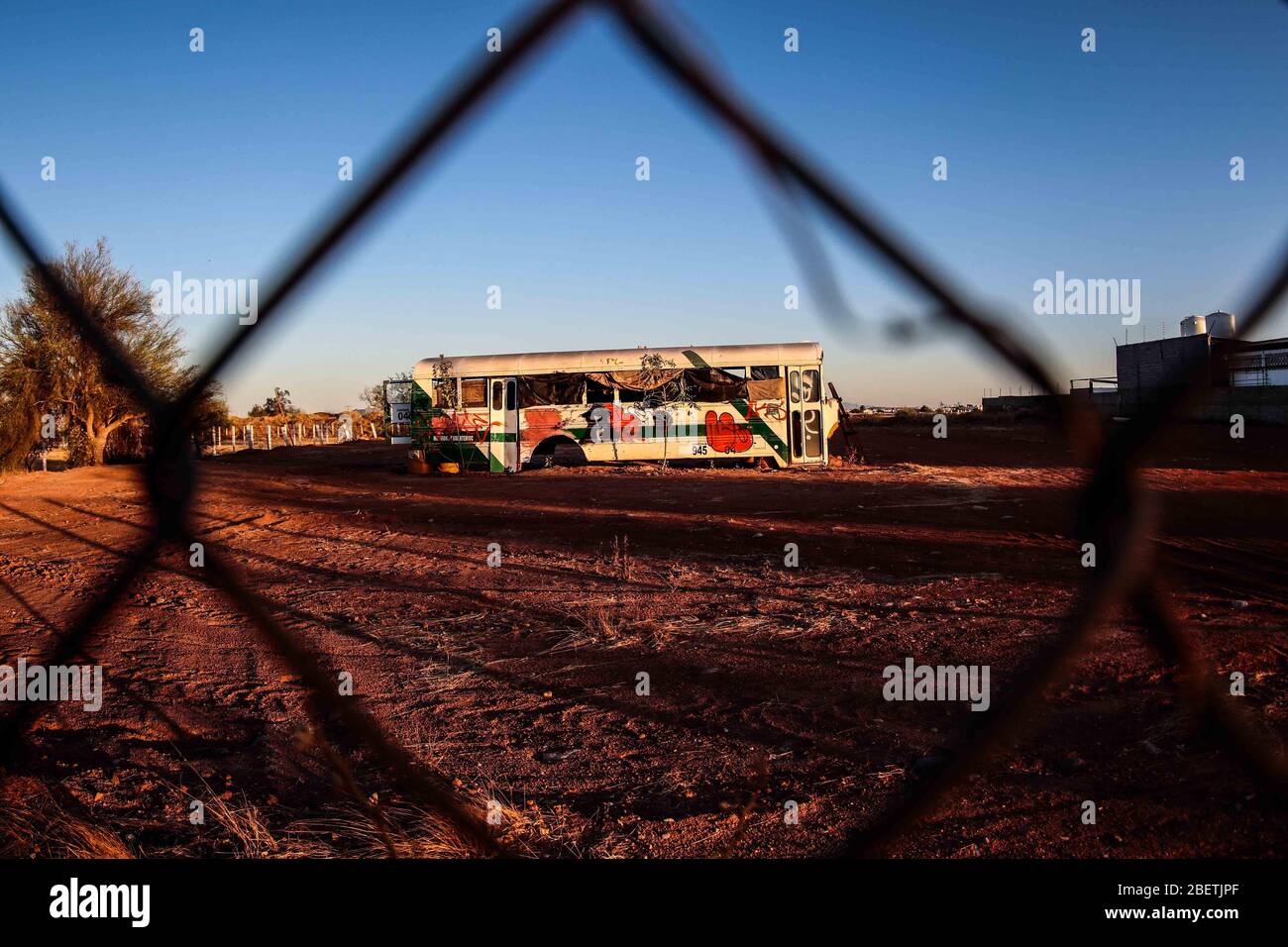 Abandoned passenger truck in La Manga neighborhood. seen through steel mesh fence.   Camion de pasajeros abandonado en la colonia la Manga. visto trav Stock Photo