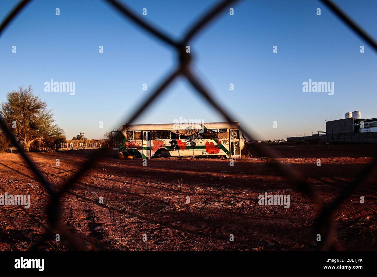 Abandoned passenger truck in La Manga neighborhood. seen through steel mesh fence.   Camion de pasajeros abandonado en la colonia la Manga. visto trav Stock Photo