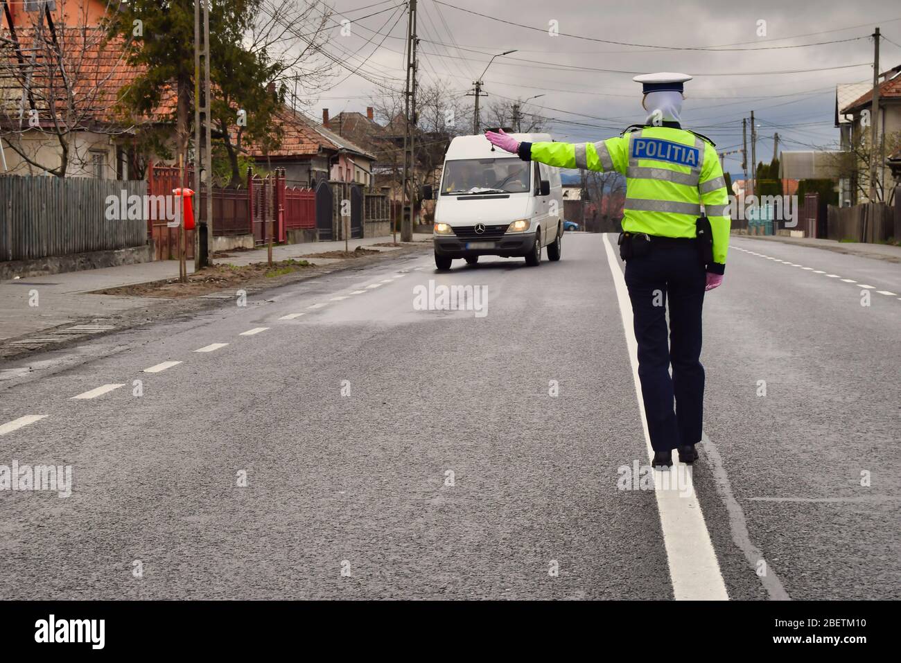 Police agent, Romanian Traffic Police (Politia Rutiera) with surgical gloves and mask are stopping cars to check driver's license and papers. Covid 19 Stock Photo