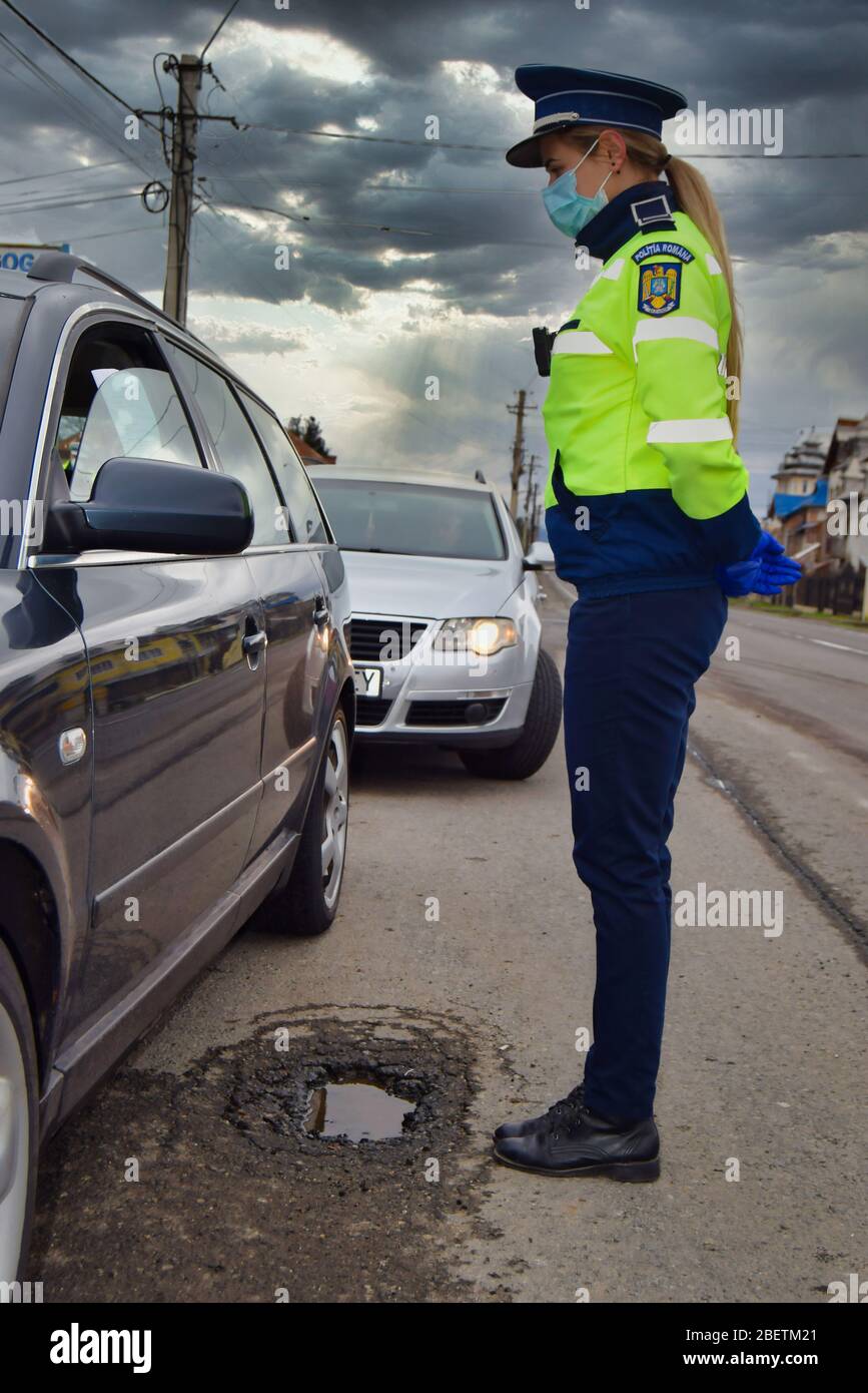 Police agent, Romanian Traffic Police (Politia Rutiera) with surgical gloves and mask are stopping cars to check driver's license and papers. Covid 19 Stock Photo
