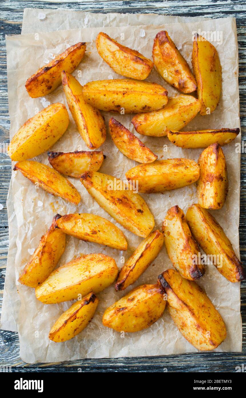 Golden spicy potato wedges fried or oven baked on wooden table. Delicious  savoury crisp snack in rustic style. Top view Stock Photo - Alamy