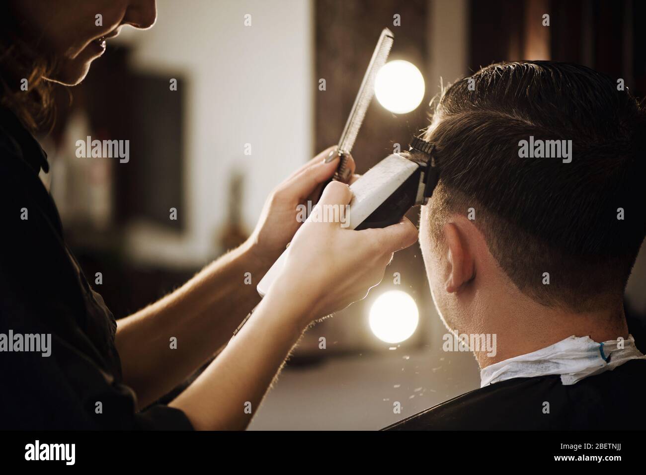 Close up view of hairdresser cutting hair of man in barbershop. Stock Photo