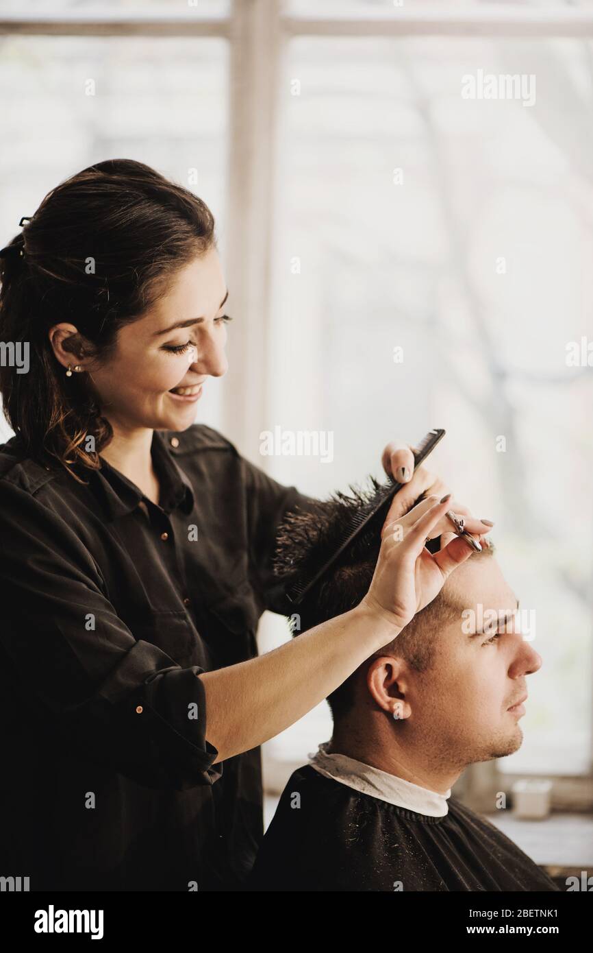 Close up view of hairdresser cutting hair of man in salon. Stock Photo