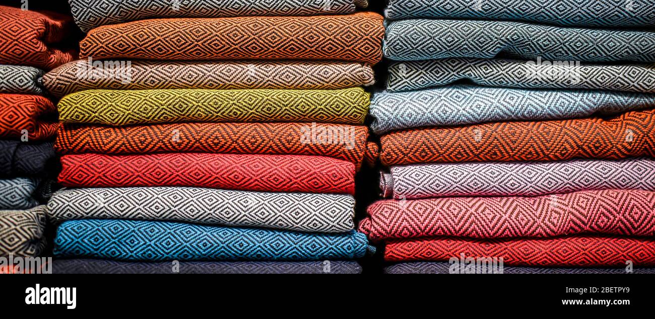 stacked multicolored clothing fabric in the closet bed linen banner Stock Photo