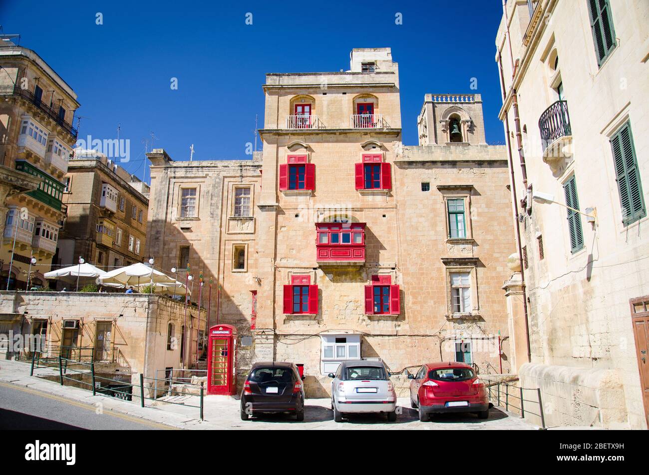 View of yellow buildings with red balconies and windows on the srteets of Valletta, Malta Stock Photo