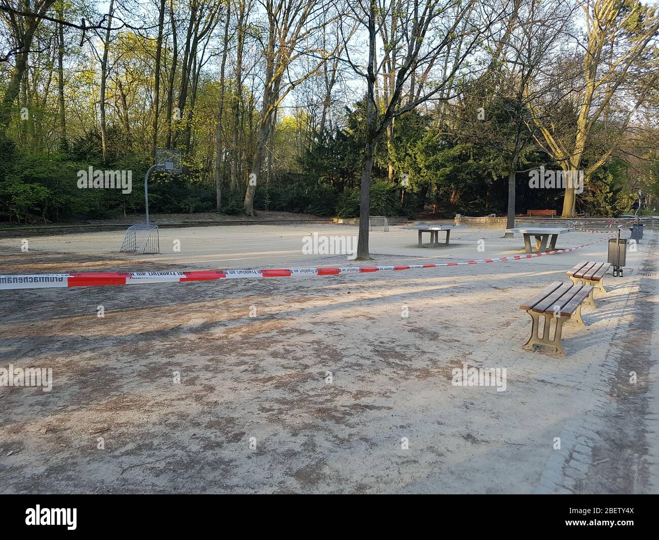 Empty, abandoned athletic ground park with basketball basket court & table tennis ping-pong closed by police barrier tape due to corona virus covid-19 Stock Photo