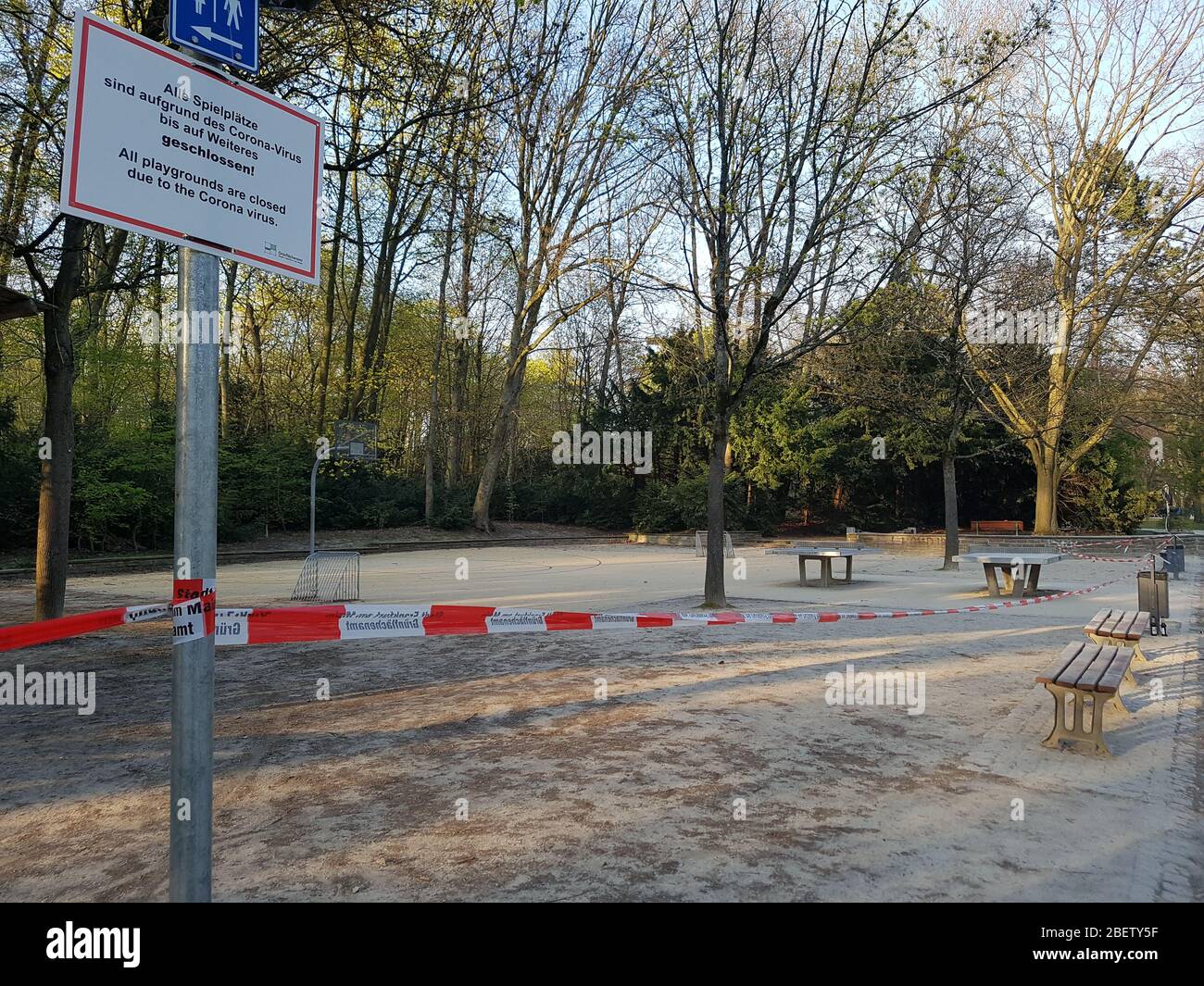 Empty, abandoned athletic ground park with basketball basket court & table tennis closed by police barrier tape & warning sign - corona virus covid-19 Stock Photo