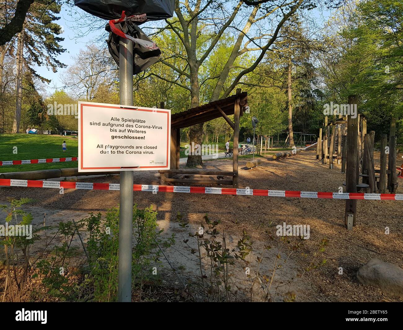 Empty , abandoned children park playground closed with police barrier tape and warning sign - prohibition to enter play field - corona virus covid-19 Stock Photo