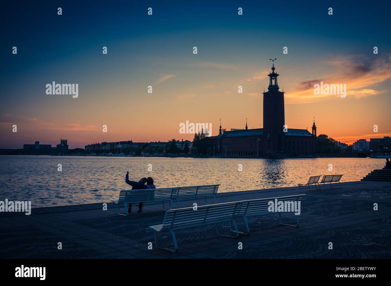 Silhouette of man and woman sitting on bench at promenade quay bank of ...