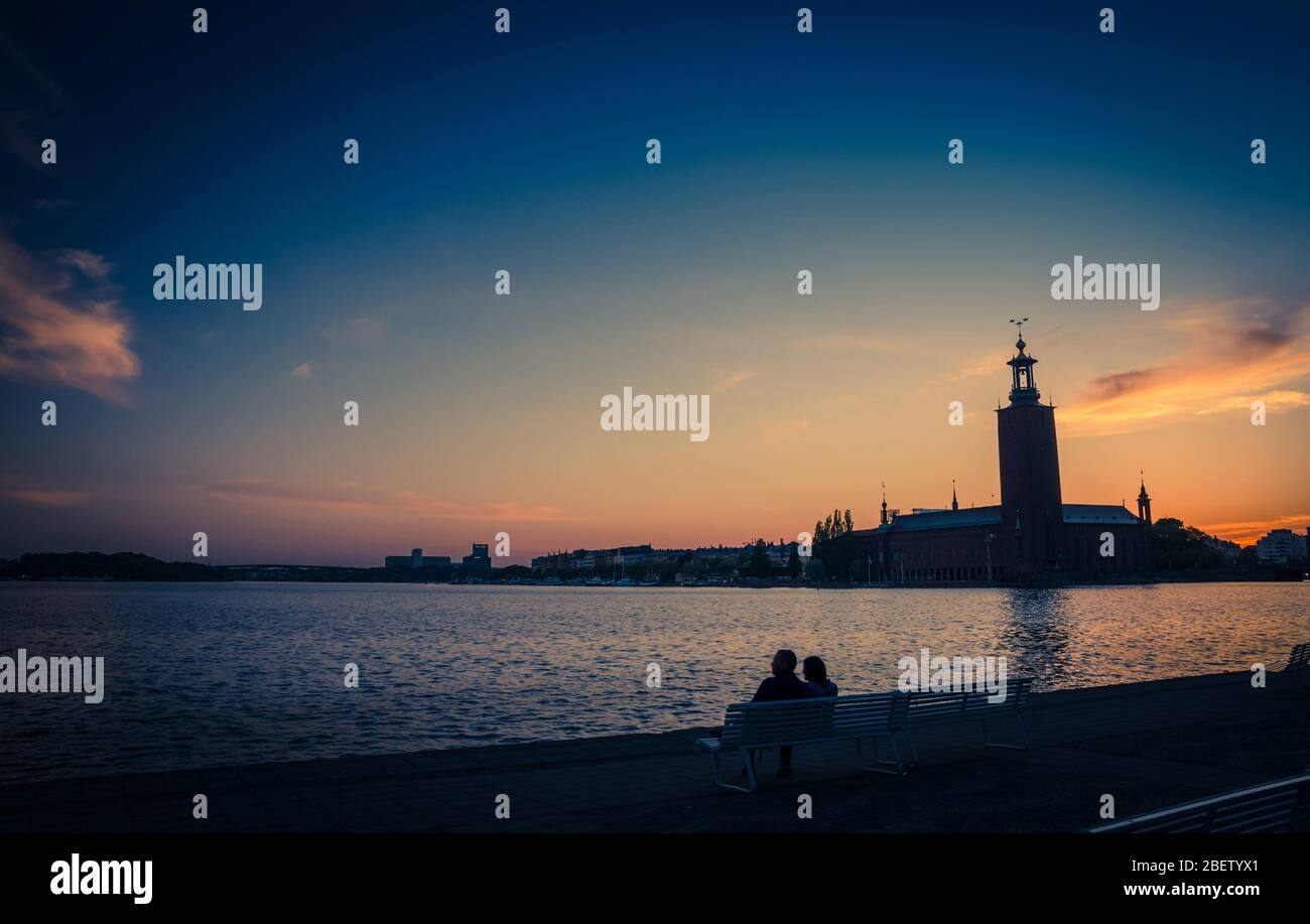 Silhouette of man and woman sitting on bench at promenade quay bank of ...