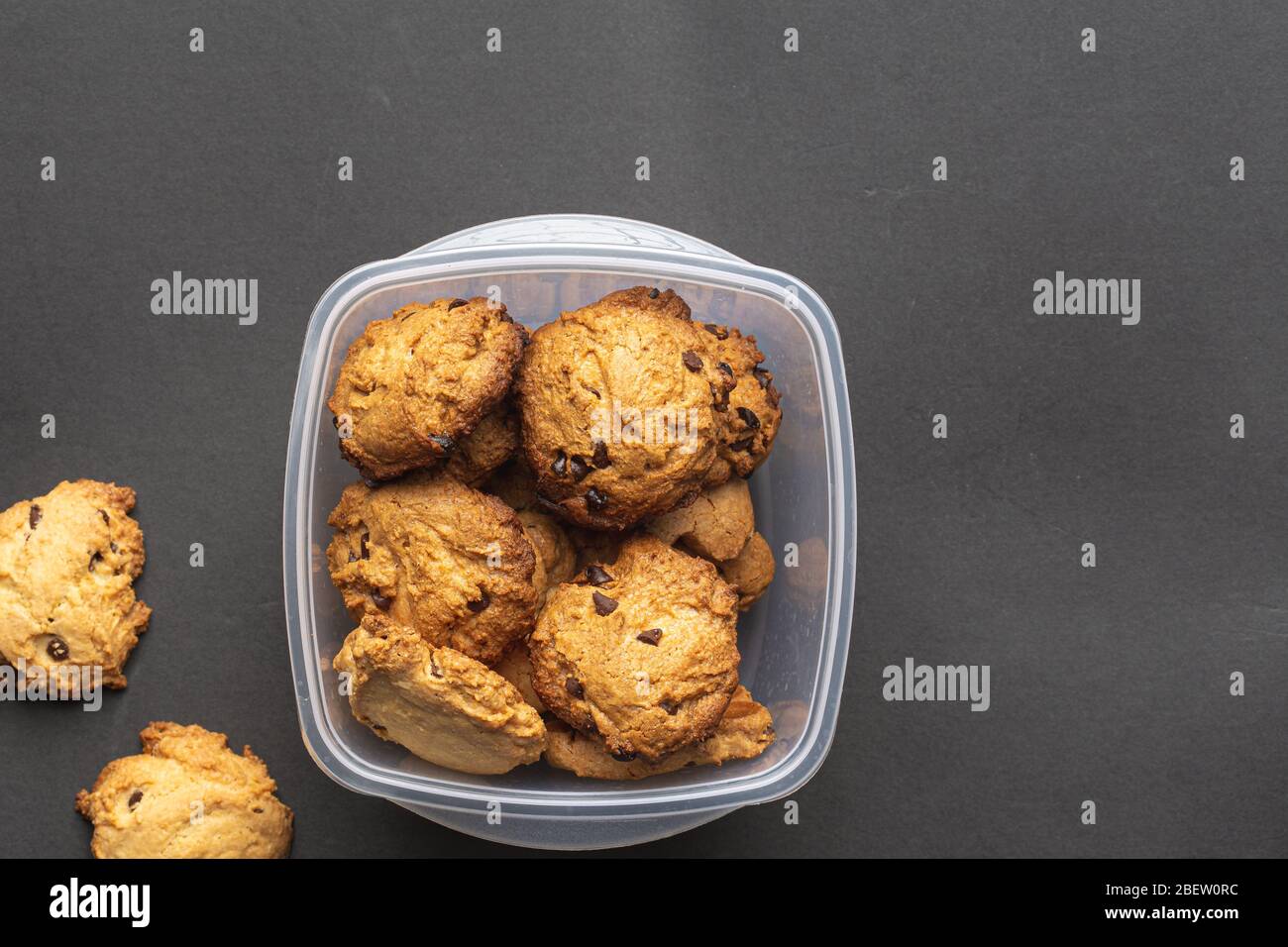 Homemade chocolate cookies on a plastic recipient on a dark grey background Stock Photo